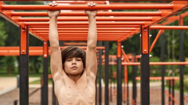 Sporcu çocuk yatay çubukta el yürüyüşü yapıyor.