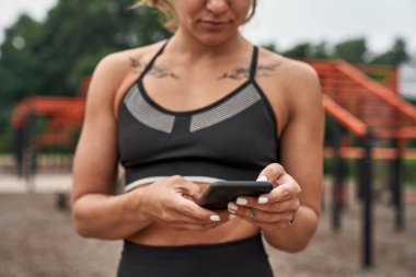 Cropped image of sports woman browsing smartphone