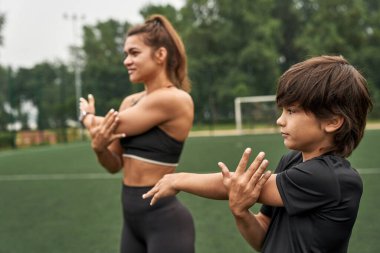 Anne ve oğlu spor sahasına el uzatıyor.