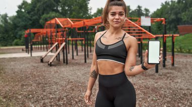 Sports woman showing smartphone on sports ground
