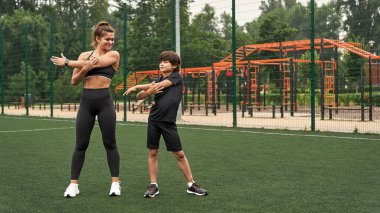 Anne ve oğlu spor sahasında ellerini ısıtıyorlar.