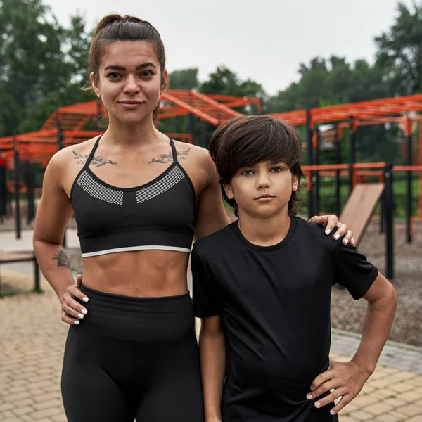 Caucasian sports mother and son with hands on hips — Stok fotoğraf
