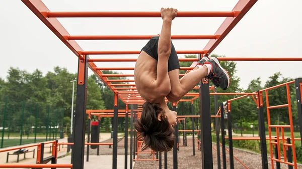 Sporcu çocuk spor sahasında yatay çubukta dönüyor.