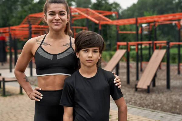 Mother and son looking at camera on sports ground — Stok fotoğraf