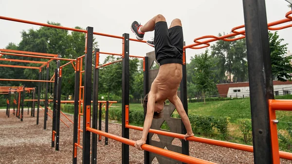 Caucasian sports boy standing on hands at training — Stok fotoğraf