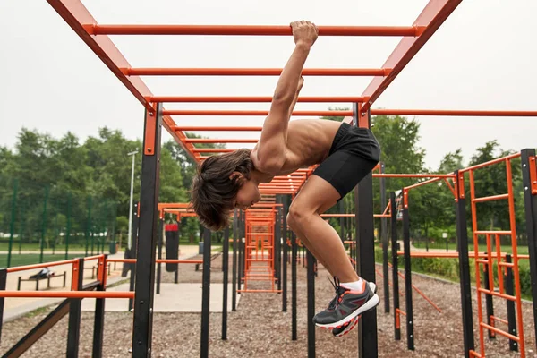 Side view of athletic boy spin on horizontal bar —  Fotos de Stock