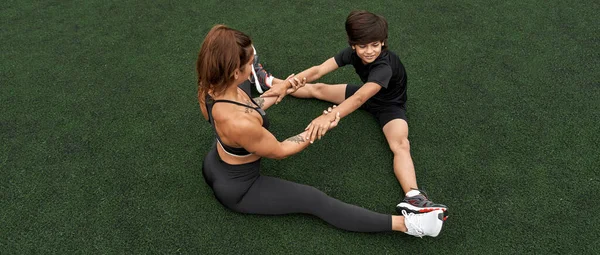 Atletik anne ve oğul ısınırken el ele tutuşun.