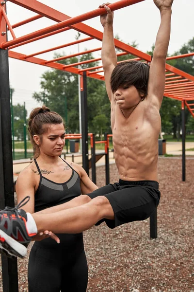 Beyaz tenli atletik anne oğluna karın kası yapmayı öğretiyor.