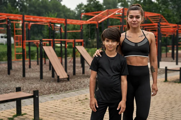 Beyaz tenli anne ve oğlu kameraya bakıyor.