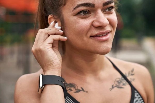 Serious sportswoman putting wireless earphone in ear — Foto Stock