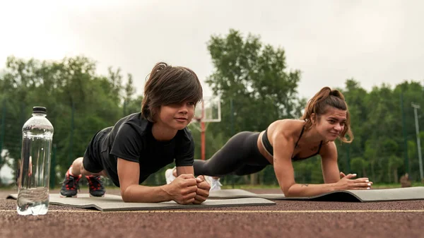 Europeisk atletisk mor och son som gör planka — Stockfoto