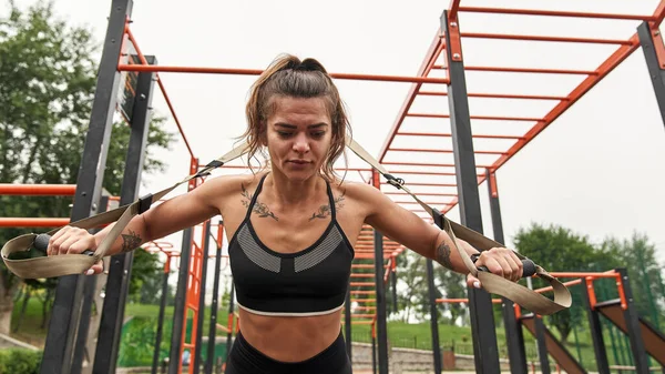 Spor sahasında kemerleriyle egzersiz yapan bir kadın.