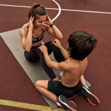 Spor sahasında annesine yardım eden bir çocuk.