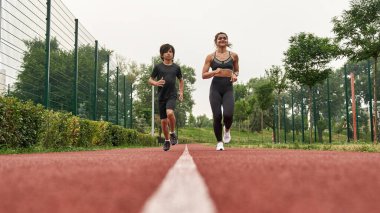 Beyaz anne ve oğlu koşu parkurunda koşuyor.