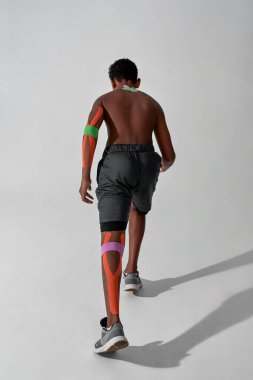 Bacağında yara bandı olan koşan bir çocuk.