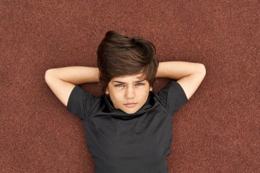 Koşu parkurunda uzanan kendine güvenen çocuğun en üst görüntüsü