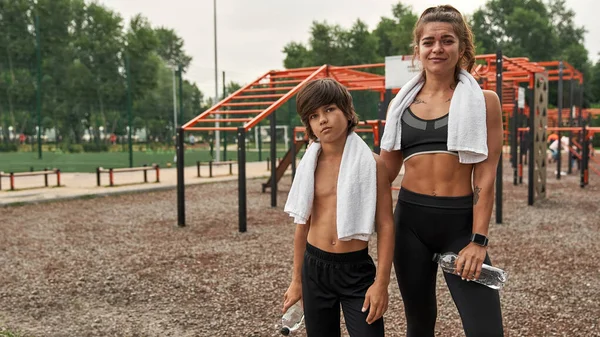 Havluları su şişeleri tutan anne ve oğlu.