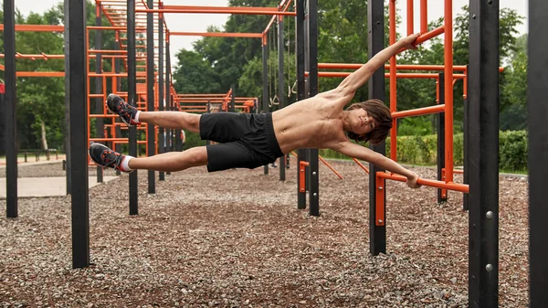 Flexibile sports boy do exercise on horizontal bar — Photo