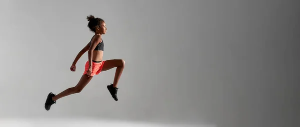 Focused athletic girl jump during run in studio — Stock Photo, Image