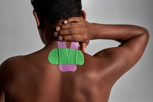 Boy touching injury neck with medical plasters — Fotografia de Stock