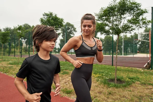 Sporcu kadın koşarken oğluna bakıyor.