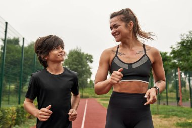Koşu parkurunda koşan gülümseyen anne ve oğul