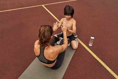 Sıska anneye çatırdama konusunda yardım eden beyaz bir çocuk.