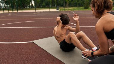 Anne oğlunun spor paspası üzerinde çıtırdatmasına yardım ediyor.