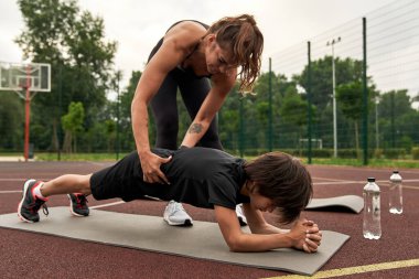 Anne, oğluna karın kasları için tahta yapmasında yardım et.