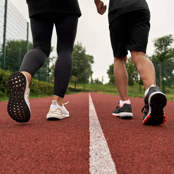 Costas parciais de mulher e menino correr na pista de corrida — Fotografia de Stock