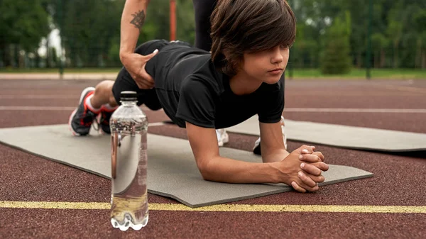 Anne, oğluna spor paspası üzerinde tahta yapmayı öğretiyor.