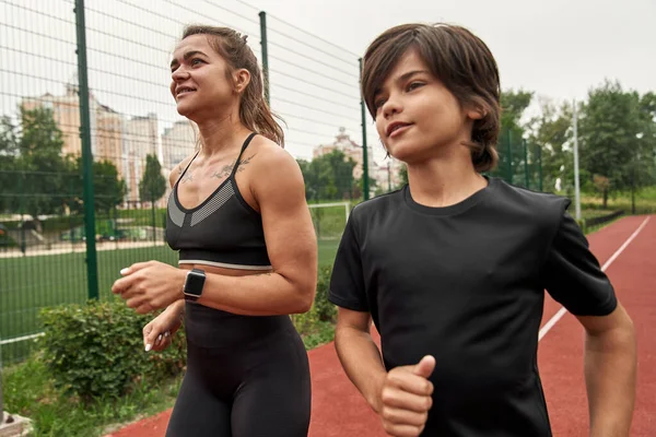 Odaklanmış anne ve oğul koşuyor ya da koşuyor.