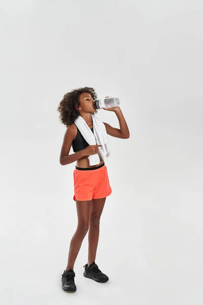 Sports girl with towel drinking water from bottle — Stok fotoğraf