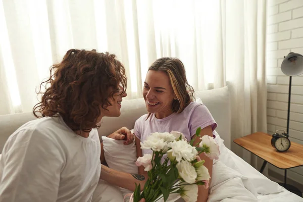 Романтичний чоловік дарує квіти дівчині на ліжку — стокове фото