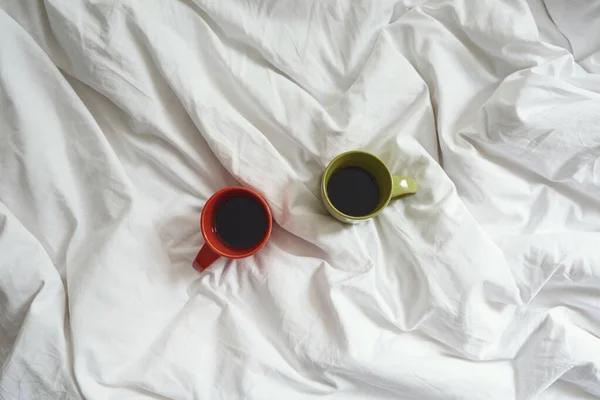 在家里的床上用茶或咖啡盖在毯子上的小杯 — 图库照片