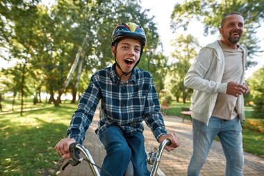 Oğlu engelli bisiklet sürerken babası koşuyor.