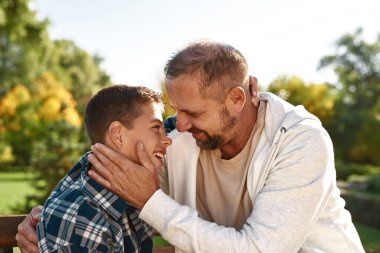Happy dad and son embrace and look at each other