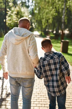 Baba ve oğul el ele tutuşup yürüyorlar.