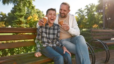 Baba yiyor ve dondurmayı besliyor.
