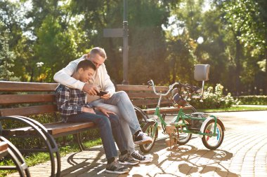 Kafkasyalı baba ve genç oğul akıllı telefon izliyor.