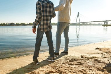 Baba ve oğul nehir kıyısında dinlenip el ele tutuşuyorlar.