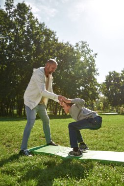 Baba, özürlü oğluna yardım et. Çimlerde mekik çek.