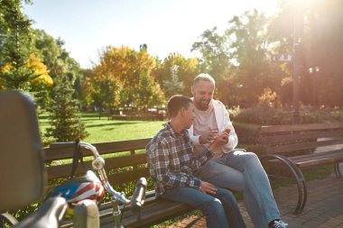 Baba, bankta beyin felci geçiren çocuğun elini tut.