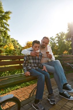 Father feed ice cream teenage son with disability