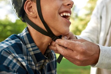 Father correct bicycle helmet on teenage son head