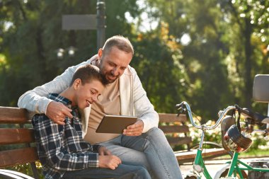 Father and son with disability use digital tablet