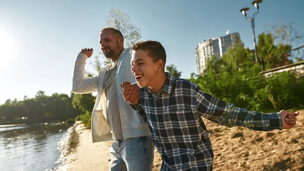 Özürlü baba ve oğlu suya taş atıyorlar.