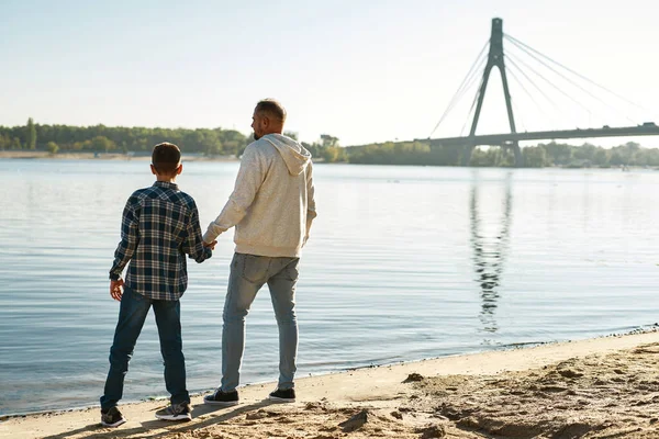 Back view of father and son stand on river coast —  Fotos de Stock