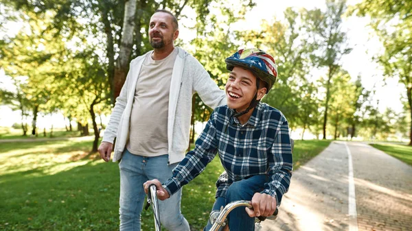 Dad walk and son with cerebral palsy ride bicycle — Stok fotoğraf