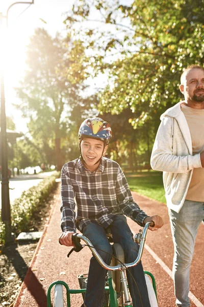 Man jogging and boy with disability riding bicycle — Stock Fotó